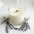 Handmade 8oz lavender soy candle in a glass jar surrounded by dried lavender sprigs